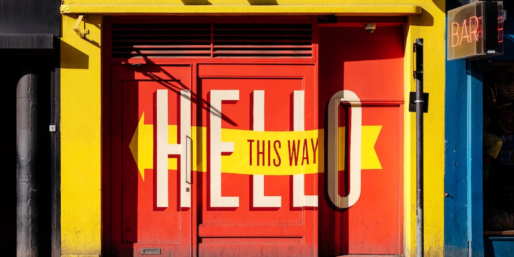 Painted wall sign reading "Hello" and "This way"